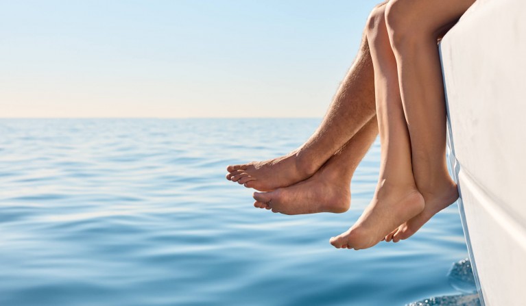 couples feet hanging off the edge of a boat