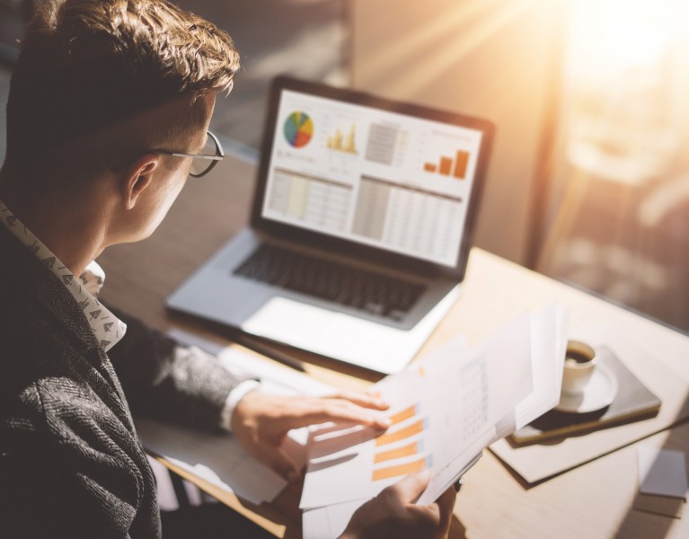 man looking at a computer and paperwork