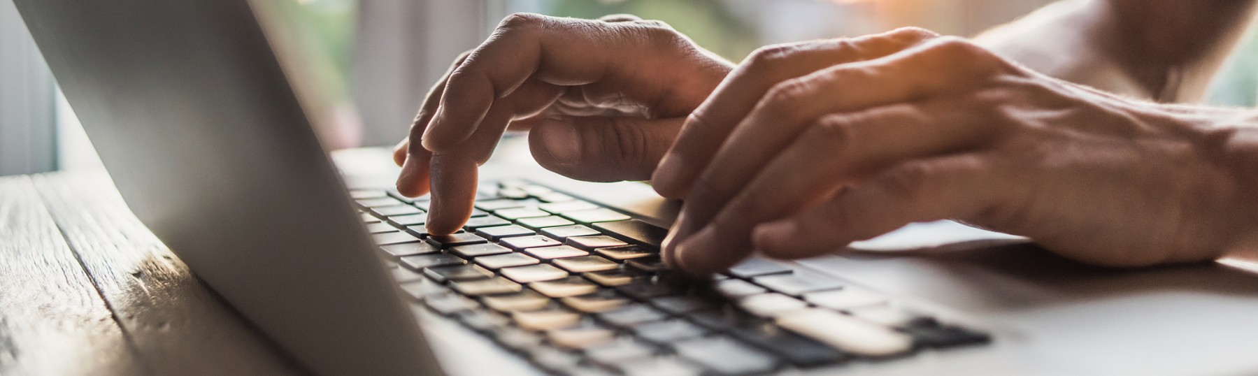 Men is typing on laptop computer keyboard