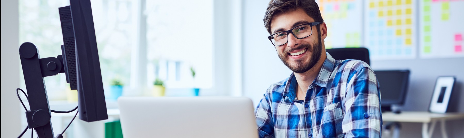 Cheerful young programmer looking at camera while working at his office