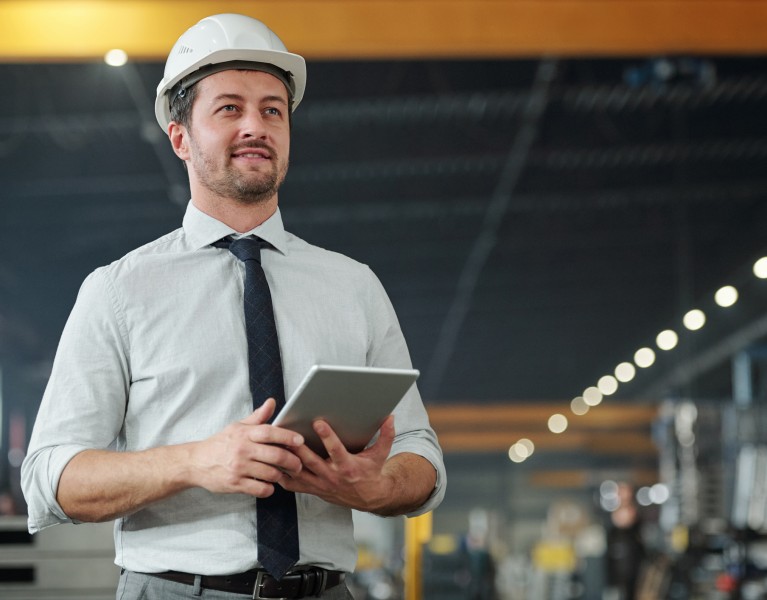 Young successful elegant foreman with touchpad working with data and controling work of industrial machine