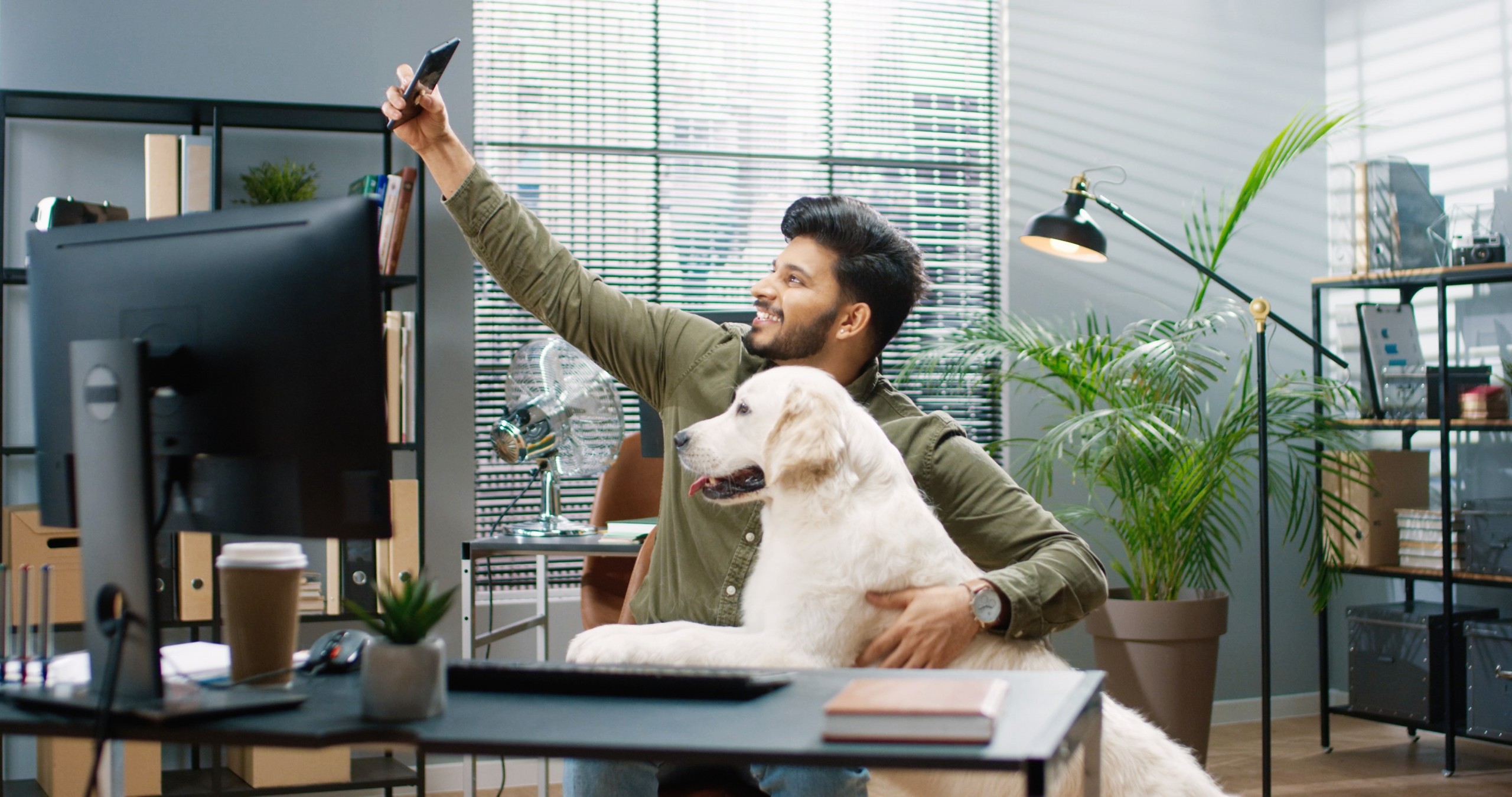 Man sits in office and takes joint photo with his big friendly dog for social media.